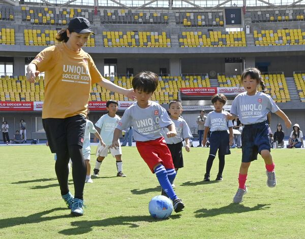鮫島さん（左）とピッチを駆ける子どもたち＝２７日午前、カンセキスタジアムとちぎ