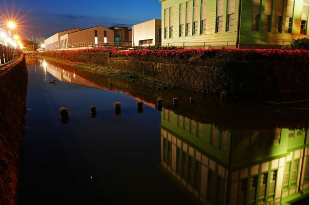 夕闇の水面に市文学館を映し出す県庁堀。石積みは１５０年前の姿を今に伝える