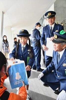 来園者に防犯グッズなどを手渡す一日警察署長（左）