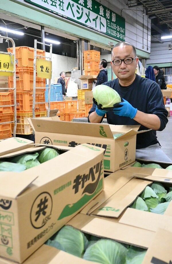 仕入れた商品を手に取る柏崎さん。日々使命感を胸に働く＝４月中旬、小山市下河原田