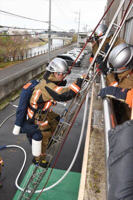 救助が必要な人に見立てた人形を背負いはしごを下りる隊員