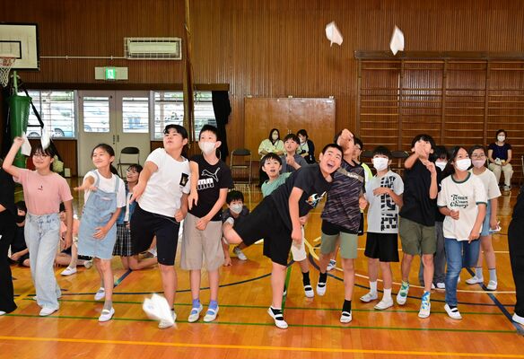 自分たちで折った紙飛行機を飛ばす児童たち