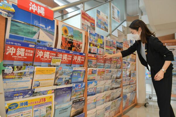 旅行パンフレットを整理する代理店スタッフ。夏休みの旅行は国内外ともに長期化、遠距離化の傾向という＝19日午後、宇都宮市池上町