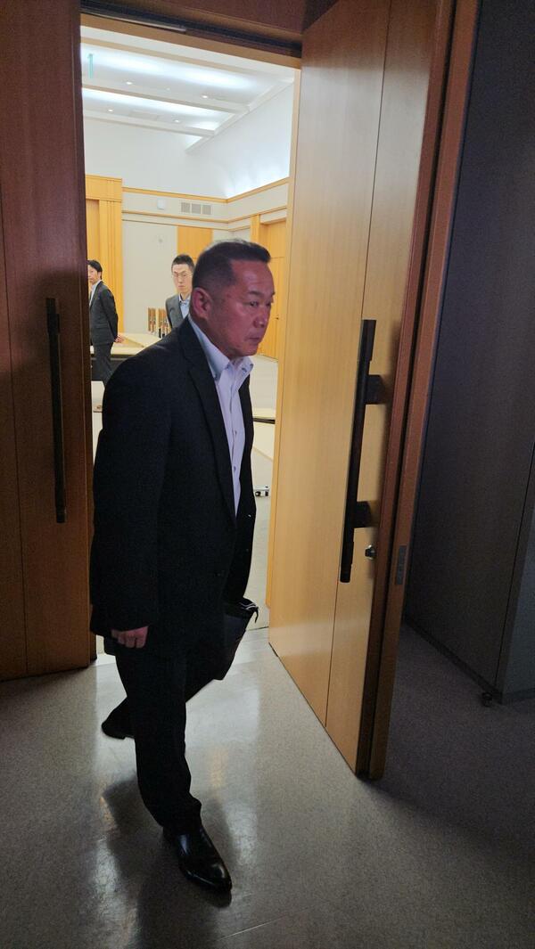 裁決書の伝達を受け会場を後にする小山田氏＝12日午前10時50分、栃木県庁