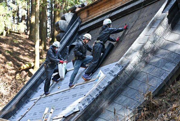 加蘇山神社の屋根に防水シートを施す星瓦店の社員ら
