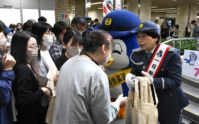 来庁者らに防犯啓発品を配る一日警察署長の大島さん（右）