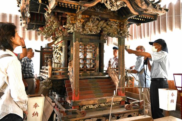 小森編集員長（右端）から高尾神社本殿の説明を受ける参加者たち