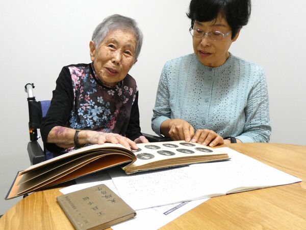 工員手帳などを手に宇都宮空襲の記憶を語る大塚さん（左）とフサさん＝11日午後、宇都宮市