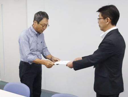 米軍と日本政府に抗議を求める文書を手渡す地元市民団体の久米慶典共同代表(左)=18日午前、山口県岩国市役所
