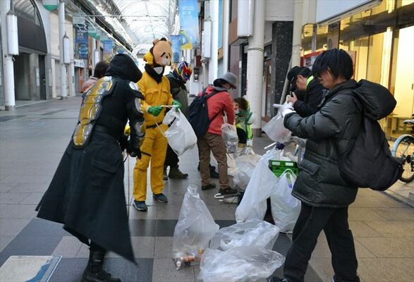 集めたごみを分別する参加者。中央の黄色いヒーローはエビフライダーマン