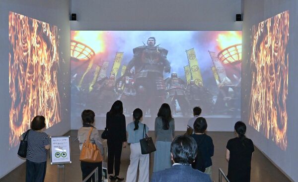 スクリーンに流れるゲームの映像を見る関係者