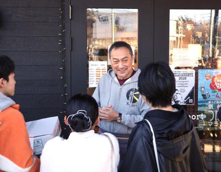 　カフェ「Ｋ―ｐｏｒｔ」の店頭で客を出迎える俳優渡辺謙さん＝２０日午前、宮城県気仙沼市