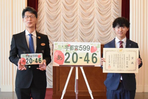 県版図柄入りナンバープレートのデザインを考案し、鈴木部長（左）から表彰を受けた杉山さん＝12日午前、県庁昭和館