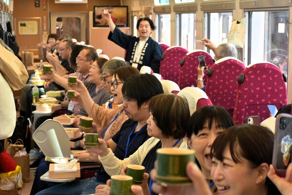宇都宮酒造の今井昌平専務(中央奥)の音頭で乾杯する地酒列車の参加者=11日午後、東京都内