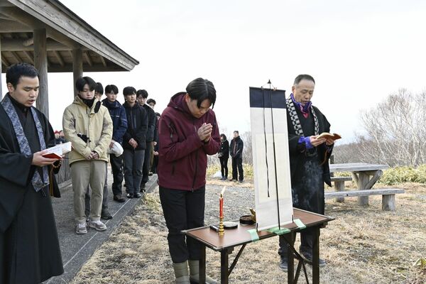 亡くなった8人の冥福を祈り手を合わせる参列者=20日午前7時10分、那須町湯本