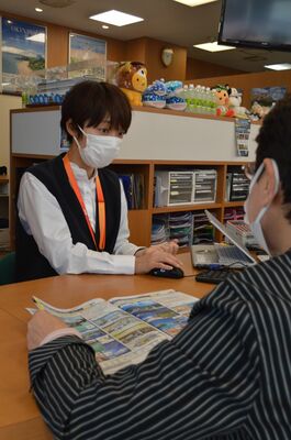 来店客に対応する代理店のスタッフ（左）。遠方を含め旅行の予約が好調という＝１４日午後、宇都宮市池上町