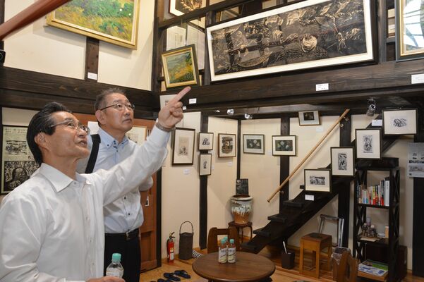 小口一郎の作品について篠崎さん（左）から説明を受ける武田町長＝７日午前、茨城県下妻市