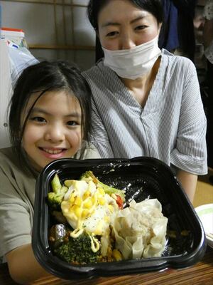 宇大生らが開発した総菜を手にする子ども