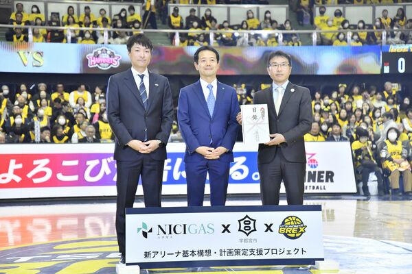 贈呈式で、日本ガスの柏谷社長（中央）から目録を受け取った宇都宮市の田中副市長（右）と、ブレックスの藤本社長＝６日午後、ブレックスアリーナ宇都宮