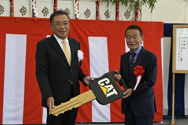 納入式で日本キャタピラーの本田博人社長（左）からマスターキーを手渡される藤坂の山野井代表取締役