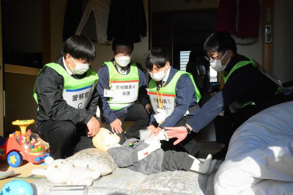 訓練で子ども役の人形のけがを調べる児相職員ら＝７日午後２時15分、宇都宮市若草２丁目