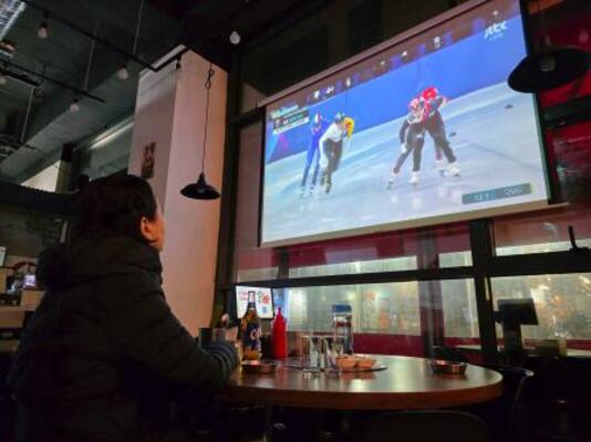 　韓国仁川市のパブで、ケーブルテレビ局が放送するミラノ・コルティナ冬季五輪の競技を見る市民＝１０日（共同）