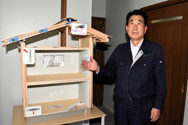 「遮熱健康住宅」体感試験棟の模型で遮熱機能を説明する野口社長＝足利市