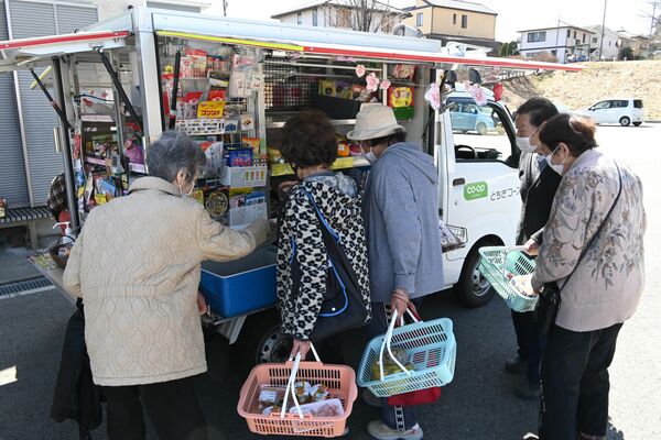 グリーンタウン自治会公民館で移動販売を利用する高齢者ら。軽トラックに生鮮食品から日用雑貨まで約４００品目がそろう