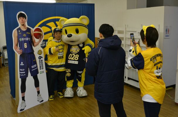 宇都宮ブレックスの比江島選手のボードやブレッキーと写真を撮るファン