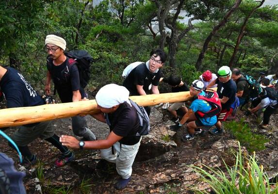 巨大な丸太を運ぶ担ぎ手たち＝昨年８月１４日