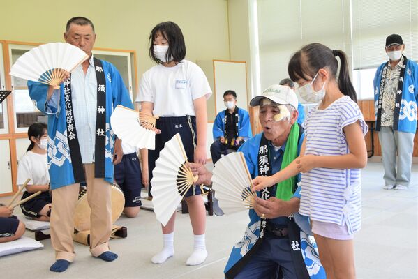 永代々神楽保存会の会員から扇子の回し方を教わる子どもたち