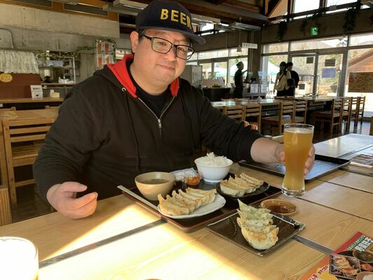 クラフトビールと餃子セットを味わうブルワリーのスタッフ