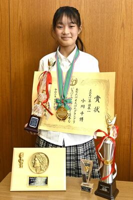 「よみあげ算日本一」のトロフィーや賞状を手にする小川さん