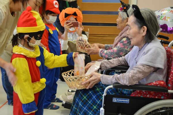 入居する高齢者から菓子のプレゼントを受け取る子どもたち