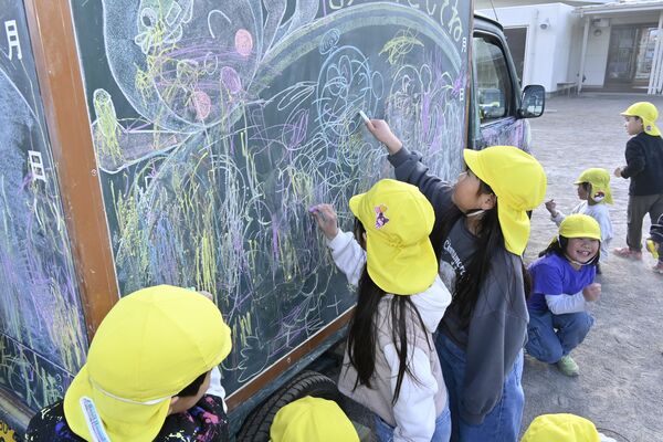 こくばんくるまに絵を描く園児ら