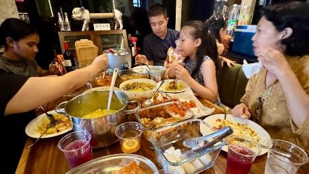 　マレーシアのスランゴール州でオープンハウスに訪れ、料理に舌鼓を打つ来客たち＝３月２８日