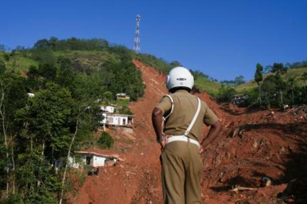 2日、スリランカ中部キャンディで、豪雨による土砂崩れの現場を見る警察官(ロイター=共同)