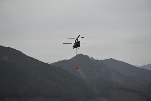 消火活動にあたる自衛隊ヘリ＝24日午前10時５分、鹿沼市上南摩町
