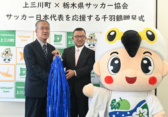 星野会長（左）に千羽鶴を手渡す星野町長＝11日午前、宇都宮市鶴田２丁目