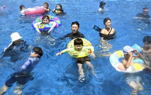 梅雨明けの青空の下、波のプールを楽しむ親子たち＝18日午後、真岡市下籠谷