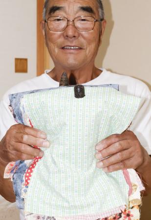 　約４００年前から家に伝わる「オシラサマ」を手にする小田正明さん＝８月、岩手県陸前高田市