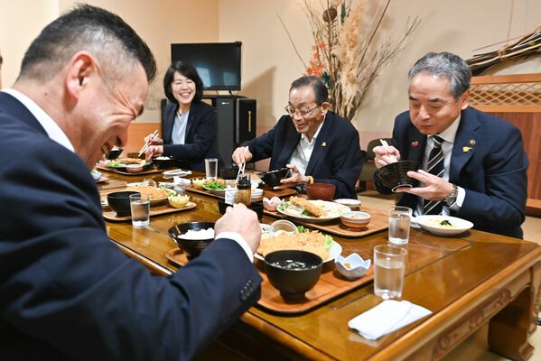 松井市長（手前）とアジフライを堪能する友田市長（右）。中央は佐藤前市長