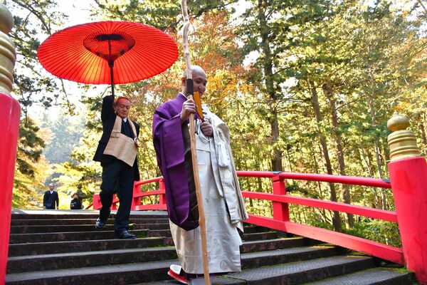 朱塗りの反り橋を渡る秦岡老師