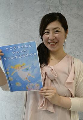 表紙のイメージ画を手にする柚木さん