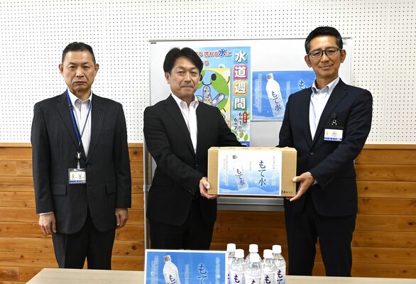 若色校長（中央）に「もて水」を手渡す古田土課長