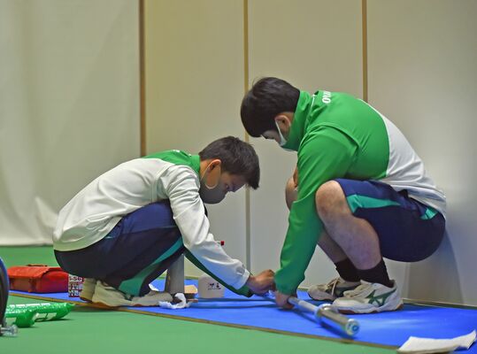 真剣な表情で重量挙げの競技用シャフトを磨く高校生＝７日午後、小山市立体育館