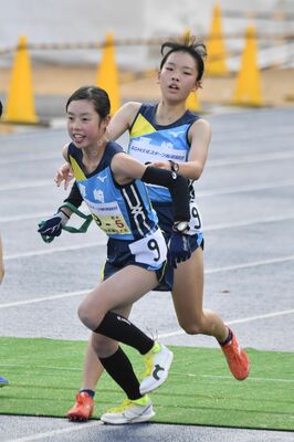 女子厚崎の4区黒川(奥)から5区一瀬にたすきをつなぐ=滋賀県の希望が丘文化公園、鈴木航撮影