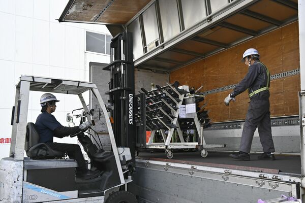 トラックから手際よく荷物を降ろすドライバーら＝17日午後、宇都宮市平出町のサンコー宇都宮営業所
