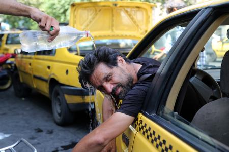 　暑さをしのぐため、水を頭からかぶるタクシー運転手＝７月、テヘラン（ゲッティ＝共同）