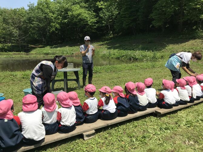 子どもたちに自然学校の生きものについて説明する遠藤さん(中央)